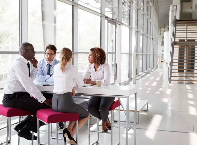 Young business people talking in a modern lobby Belinos Consulting training London